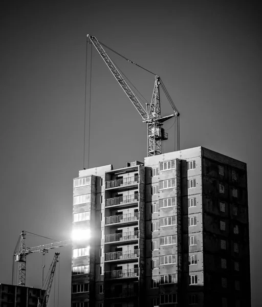 silhouettes of industrial construction cranes and building