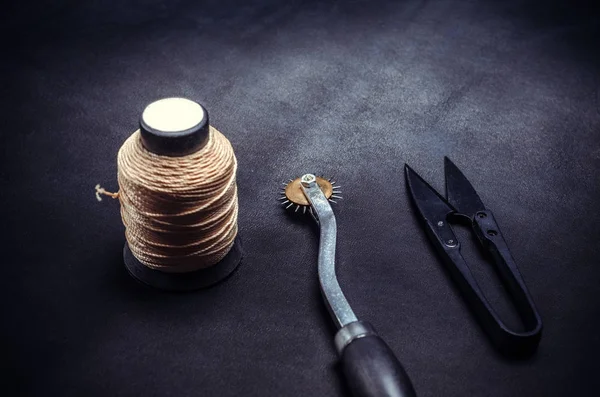 Spule aus gelben Fäden und Werkzeugen auf schwarzem Hintergrund — Stockfoto