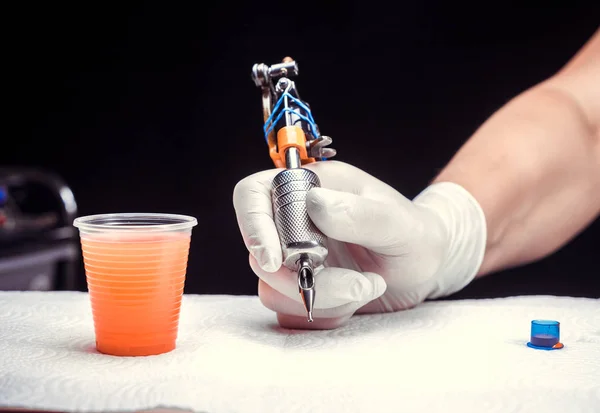 Hand of a tattooer, carefully holding a tattoo device. — Stock Photo, Image