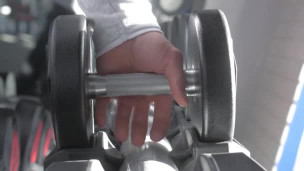 Una mano de hombre toma una pesa en el gimnasio. De cerca. Brazo muscular en el gimnasio. Entrenamiento, deportes, mano, pesa. El concepto de un estilo de vida saludable . — Vídeos de Stock