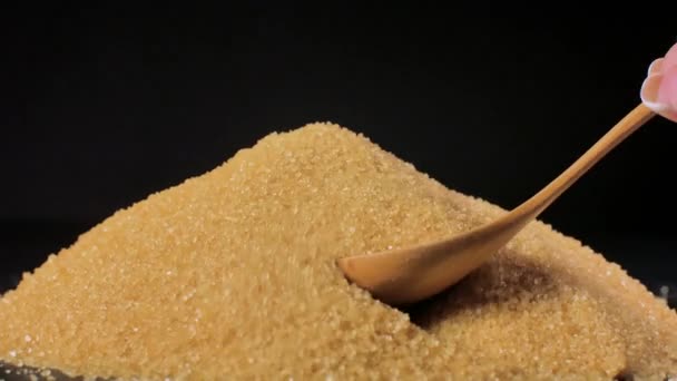 Azúcar de caña sin refinar. Un montón de azúcar se mezcla con una cuchara de madera . — Vídeos de Stock