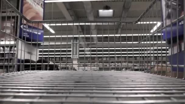 Viewing a shopping cart in a supermarket aisle with food shelves — Stock Video