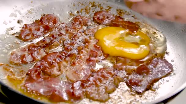 Szalonnát és tojást sütni egy ezüst serpenyőben. Házi készítésű reggeli készítése. — Stock videók