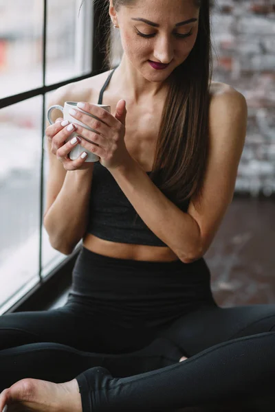 Young Woman in Her Pajamas Sitting in a Window Drinking out of a Mug