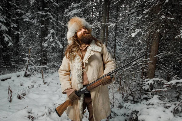 Hunter man in winter warm vintage clothes with gun in winter for