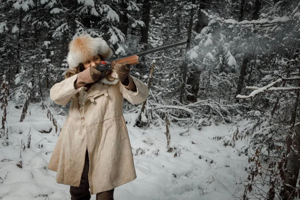 Hunter in winter vintage clothes shoots gun in forest