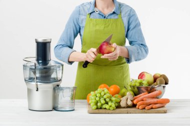 Modern elektrikli meyve sıkacağı, sağlıklı yaşam konsepti üzerine beyaz arka plan kullanarak sağlıklı meyve suyu hazırlama başlamak için hazır bir önlük giyen anonim kadın