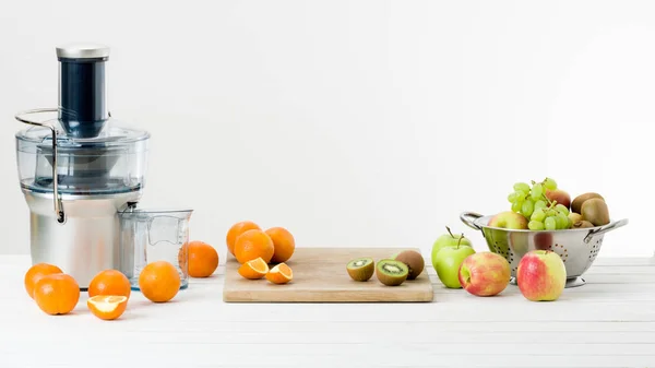 Exprimidor eléctrico moderno y varias frutas en el mostrador de la cocina, concepto de estilo de vida saludable — Foto de Stock