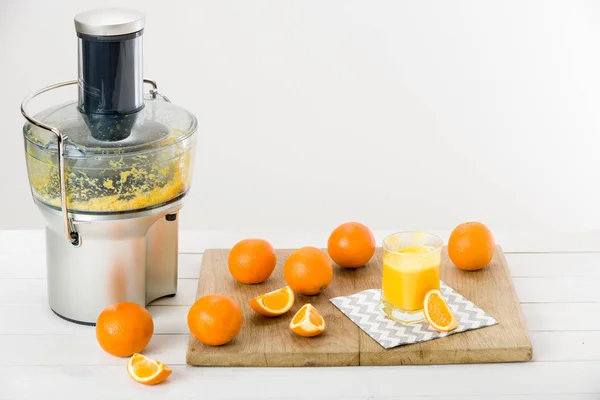 Modern electric juicer and freshly prepared orange juice, white background — Stock Photo, Image