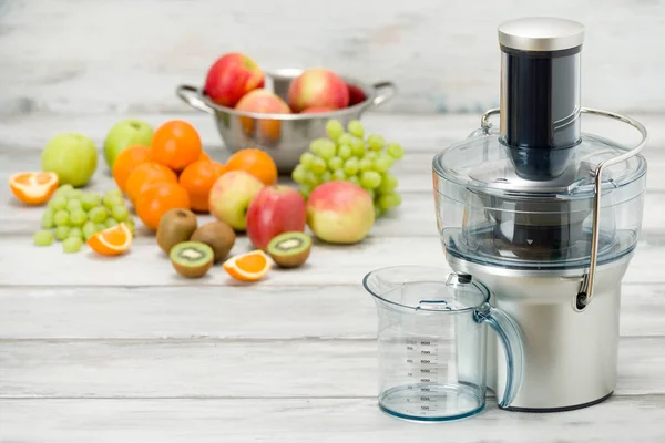 Juicer elétrico moderno e várias frutas no balcão da cozinha, conceito de estilo de vida saudável — Fotografia de Stock