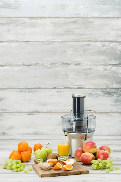 Juicer elétrico moderno, várias frutas e vidro de suco acabado de fazer, conceito de estilo de vida saudável — Fotografia de Stock