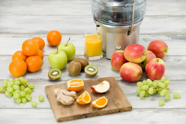 Exprimidor eléctrico moderno, varias frutas y vasos de jugo recién hecho, concepto de estilo de vida saludable — Foto de Stock