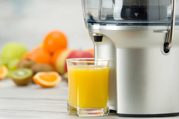 Juicer elétrico moderno, várias frutas e vidro de suco acabado de fazer, conceito de estilo de vida saudável — Fotografia de Stock