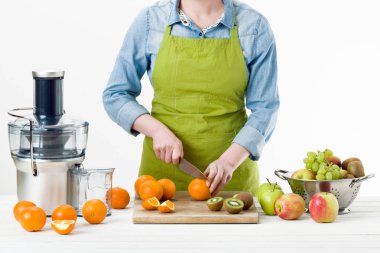 Modern elektrikli meyve sıkacağı, sağlıklı yaşam konsepti üzerine beyaz arka plan kullanarak taze sıkılmış meyve suyu hazırlama bir önlük giyen anonim kadın