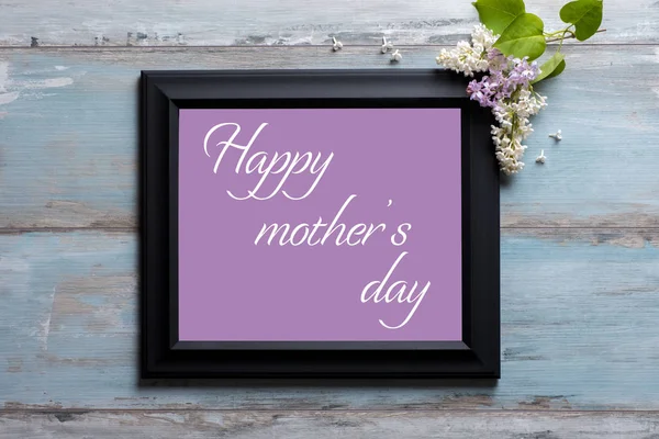 Marco de fotos con flores lila y mensaje del día de la madre feliz sobre fondo azul de madera — Foto de Stock