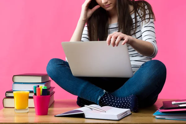 Приваблива біла дівчина вчиться на іспити вдома, студент сидить на столі з ноутбуком на колінах — стокове фото
