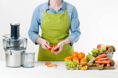 Modern elektrikli meyve sıkacağı, sağlıklı yaşam konsepti üzerine beyaz arka plan kullanarak taze sıkılmış meyve suyu hazırlama bir önlük giyen anonim kadın