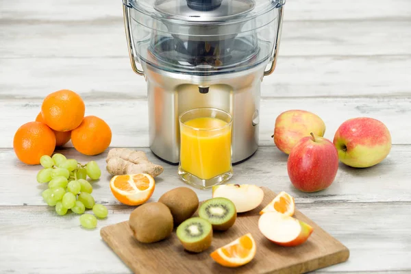 Presse-fruits électrique moderne, divers fruits et verre de jus fraîchement fait, concept de mode de vie sain — Photo