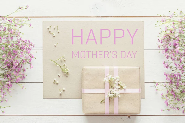 Fondo del día de la madre, mesa de madera blanca con flores rosadas y un regalo — Foto de Stock