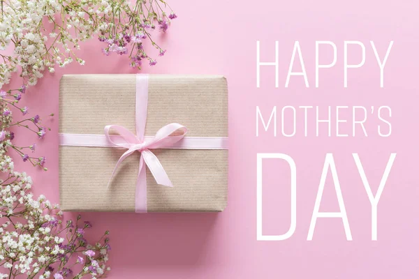 Tarjeta del día de la madre, fondo rosa con flores blancas y un regalo — Foto de Stock