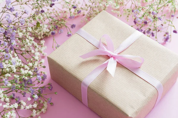 Fondo rosa con flores lila y blanca y un regalo, concepto del día de la madre — Foto de Stock