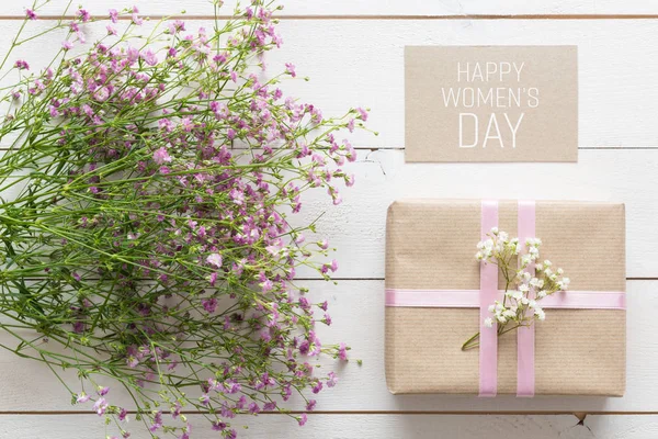 Fond de journée des femmes, table en bois blanc avec des fleurs roses et un cadeau — Photo