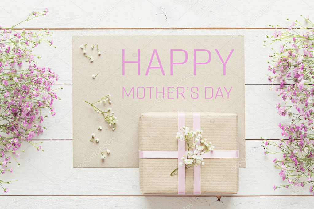 Mother's day background, white wooden table with pink flowers and a present