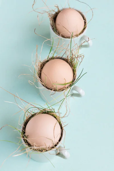 Uncolored natural easter eggs in espresso cups; happy easter concept; green minimalist easter background — Stock Photo, Image