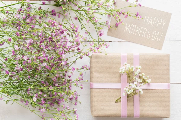 Mesa de madera blanca con flores rosas y un regalo, concepto del día de la madre — Foto de Stock