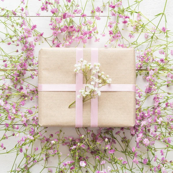 Table en bois blanc avec des fleurs roses et un cadeau, concept de fête des mères — Photo