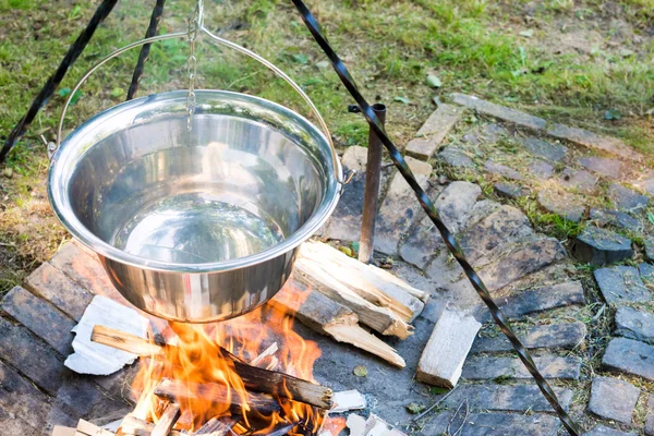 Cooking food on fire outdoors. Cooking outdoors in cast-iron cauldron.