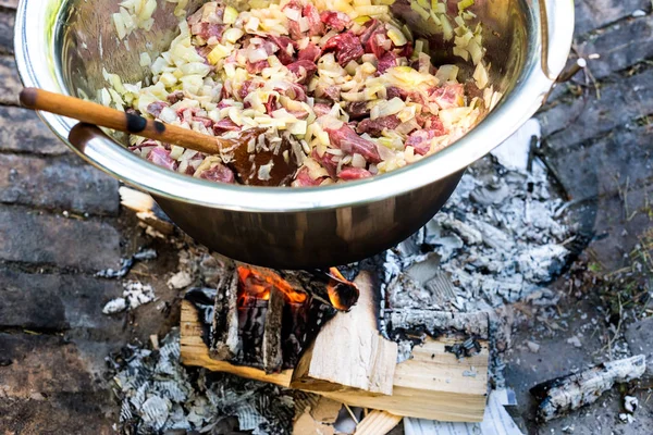 在户外的火上做饭。蒸煮炖牛肉或炖菜在户外的铸铁锅. — 图库照片