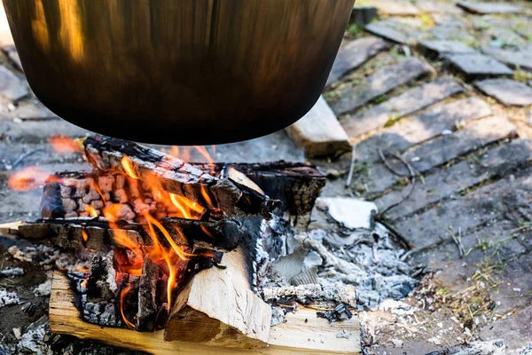 Cooking food on fire outdoors. Cooking outdoors in cast-iron cauldron.