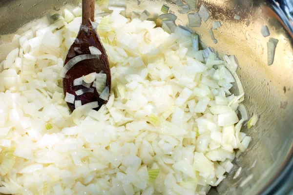 Fried sliced white onions in a pan with wooden spoon — Stock Photo, Image