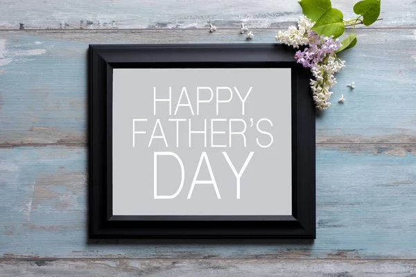 Picture frame with lilac flowers and Happy Father's day message on blue wooden background — Stock Photo, Image