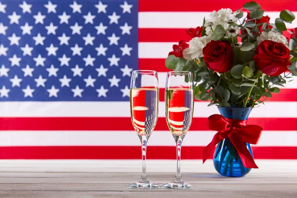 Hermoso ramo, bandera americana y dos copas de champán — Foto de Stock