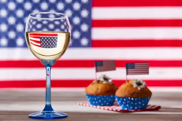 Bandera americana, copa de vino blanco y magdalenas lindas — Foto de Stock