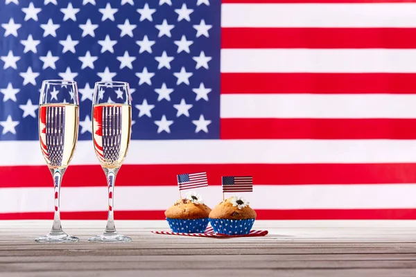 Bandera americana, dos copas de champán y lindos cupcakes — Foto de Stock