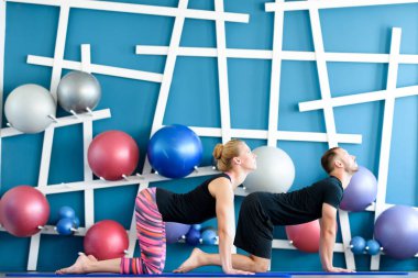 Güzel bir çift bir stüdyoda Yoga yapıyor. Yoga sınıfındaki inek gençlerin poz. Yoga grup kavramı.
