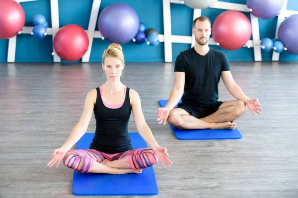 Güzel bir çift bir stüdyoda Yoga yapıyor. Yoga sınıfındaki lotus pozisyonu genç insanlar. Yoga grup kavramı. — Stok fotoğraf