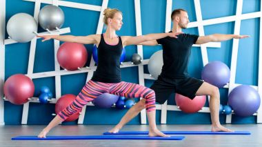 Güzel bir çift bir stüdyoda Yoga yapıyor. Gençler savaşçı yoga sınıfındaki poz. Yoga kavramı.