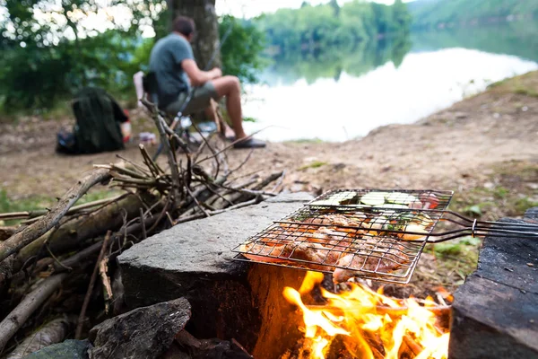 Fiskare som förbereder middag på lägerelden, äventyr camping fiske semester livsstilskoncept — Stockfoto