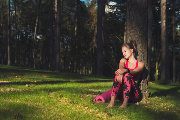 Junge attraktive athletische Frau mit smarter Uhr genießt die letzten Sonnenstrahlen für den Tag nach ihrem Training im Wald — Stockfoto