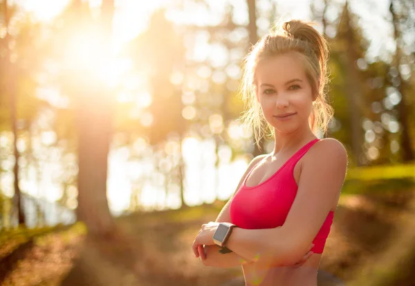 Aantrekkelijke fit atletische vrouw in een forest, het dragen van slimme horloge, het nemen van een pauze van intensieve training. Sport, fitness, training concept — Stockfoto