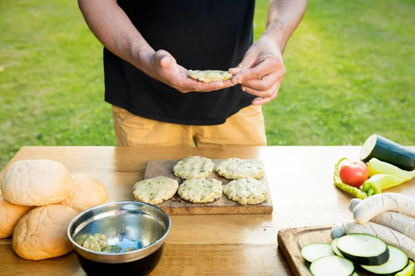 Snygg hipster man förbereder kött och zucchini hamburgare, bbq sommar trädgård matkoncept — Stockfoto