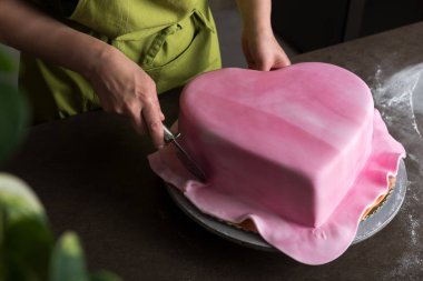 Fırın dekorasyon kalp şeklinde pastanın pembe fondan ile unrecognisable kadında görüntülemek yukarıdan
