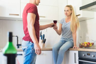 Çekici genç beyaz adam mutfak tezgahına, kırmızı şarap oturan arkadaşı sunan