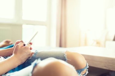 Bir kanepede rahatlatıcı modern evinde oturan genç unrecognisable kadın. Örümcek ağı browsing hareket eden telefon, tutan kadın