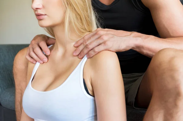 Невідомий чоловік сидить на дивані, даючи свою красиву дружину шию і плечовий масаж вдома — стокове фото
