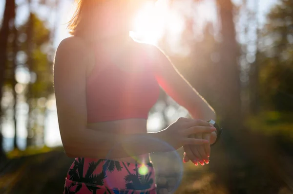 Aantrekkelijke vrouwelijke atleet met behulp van fitness app op haar slimme horloge training prestaties controleren. — Stockfoto